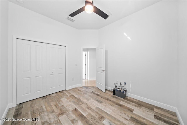 unfurnished bedroom with a closet, visible vents, a ceiling fan, wood finished floors, and baseboards