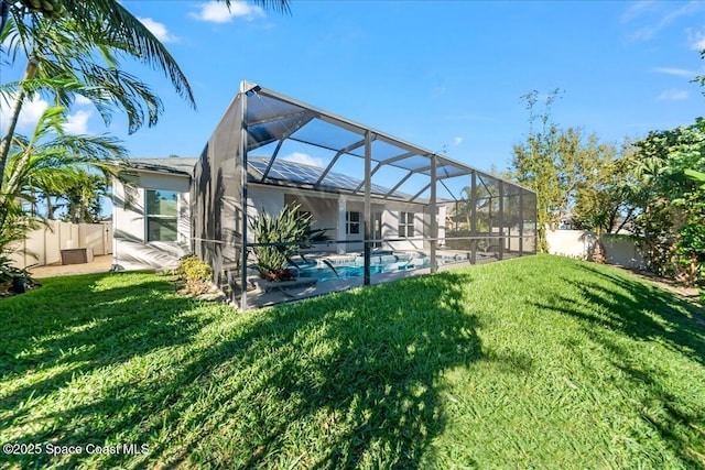 back of house featuring a yard, a patio, glass enclosure, a fenced backyard, and an outdoor pool