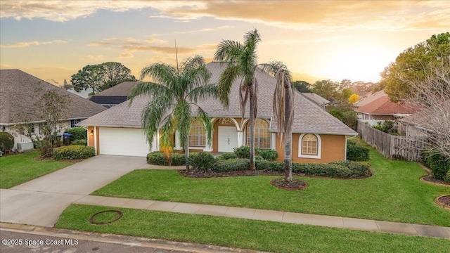 view of front facade with a garage, driveway, fence, and a yard