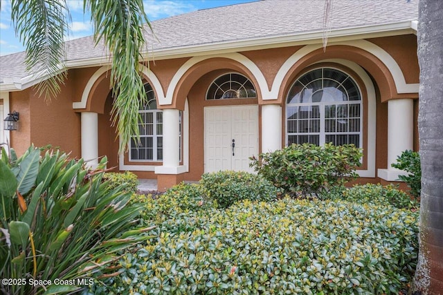 doorway to property featuring a shingled roof and stucco siding