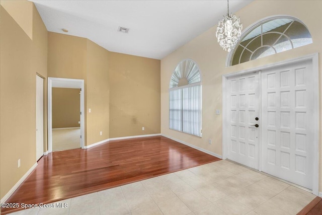 entryway featuring baseboards, visible vents, light wood finished floors, and an inviting chandelier