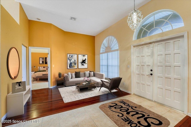 entrance foyer featuring high vaulted ceiling, an inviting chandelier, visible vents, and tile patterned floors