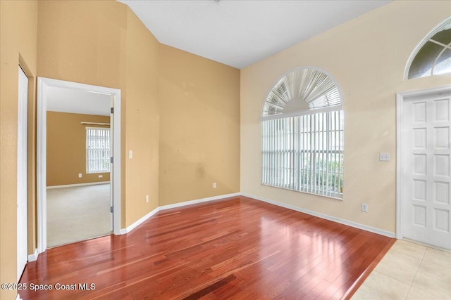 unfurnished room with lofted ceiling, wood finished floors, and baseboards