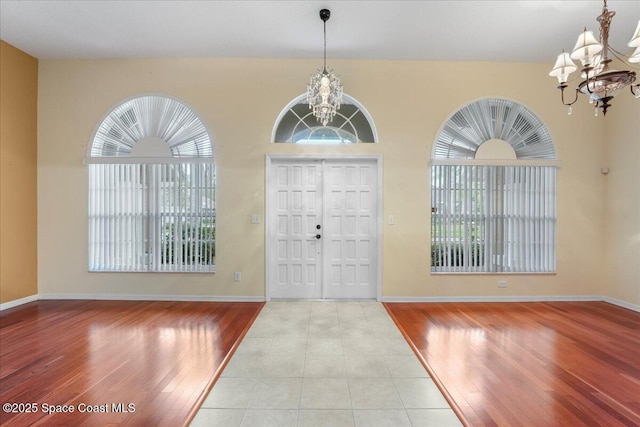 foyer entrance featuring a chandelier, light wood finished floors, and baseboards