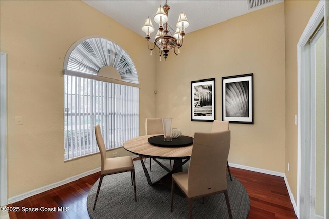 dining area featuring dark wood-type flooring, an inviting chandelier, visible vents, and baseboards