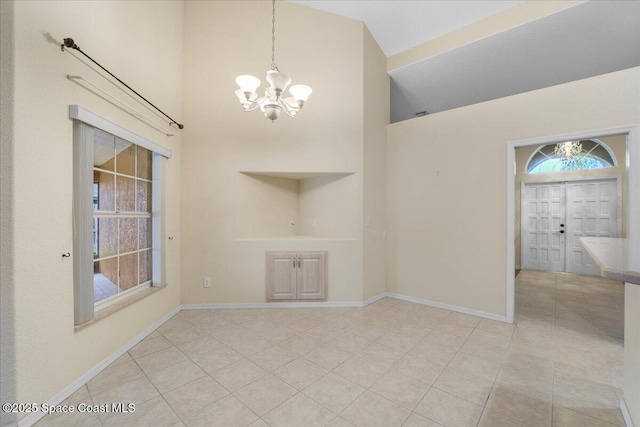 interior space featuring high vaulted ceiling, an inviting chandelier, tile patterned floors, and baseboards