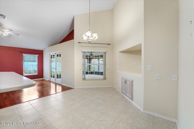 interior space with light tile patterned floors, visible vents, baseboards, high vaulted ceiling, and ceiling fan with notable chandelier