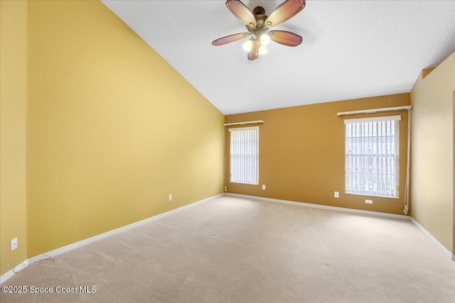 unfurnished room featuring light carpet, vaulted ceiling, and baseboards