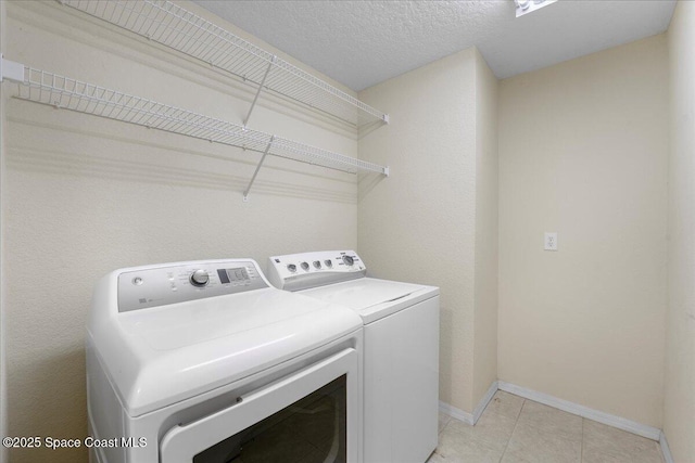 laundry room featuring laundry area, light tile patterned floors, baseboards, a textured ceiling, and washer and dryer