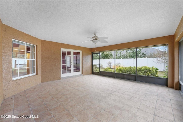 unfurnished sunroom with ceiling fan, french doors, and a healthy amount of sunlight