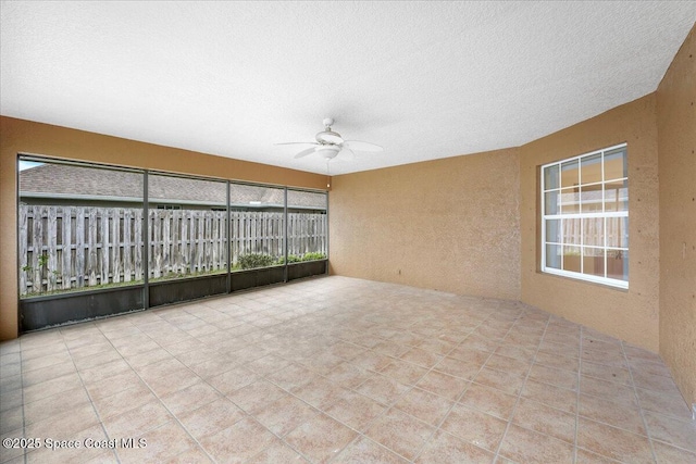 unfurnished sunroom featuring a ceiling fan and a healthy amount of sunlight