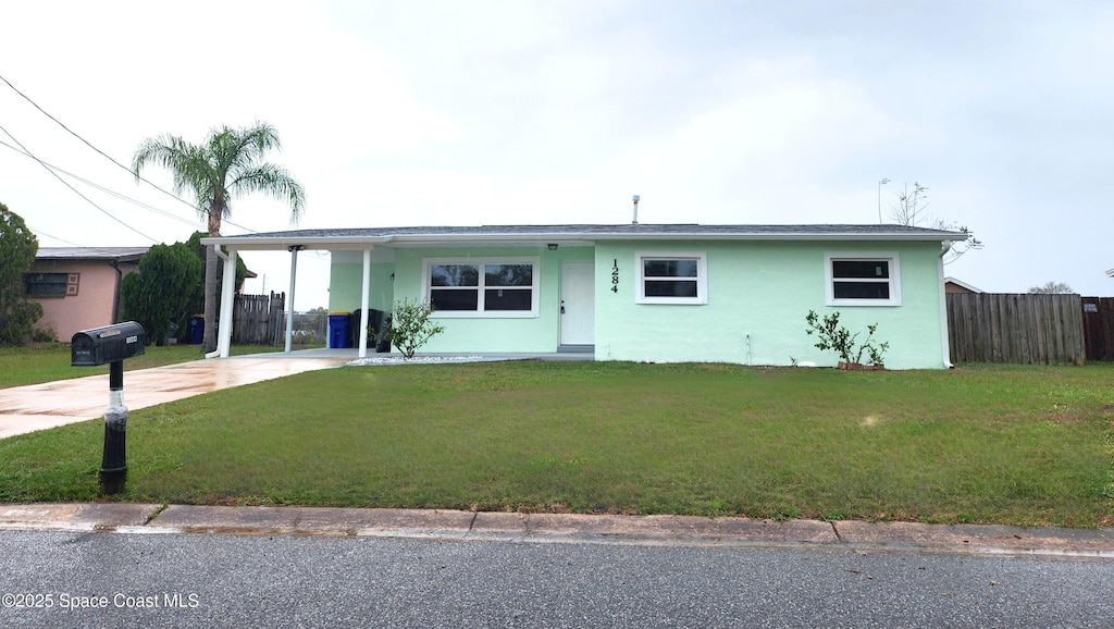 ranch-style house with driveway, a front lawn, fence, and stucco siding