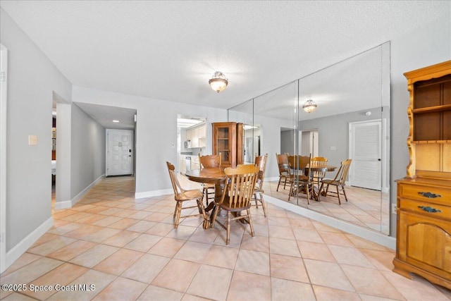 dining room with a textured ceiling, baseboards, and light tile patterned floors