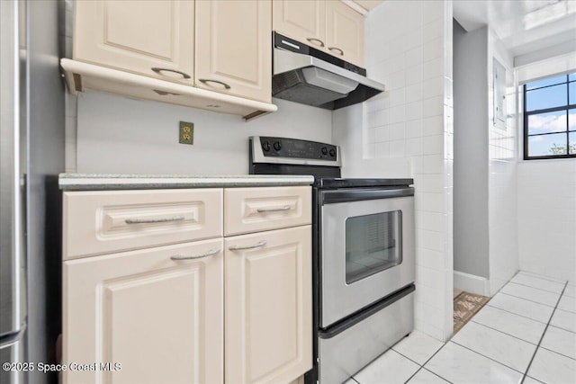 kitchen featuring under cabinet range hood, stainless steel electric range oven, light tile patterned floors, and light countertops