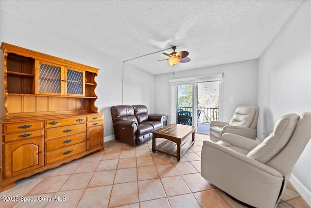 living room with light tile patterned floors, ceiling fan, a textured ceiling, and baseboards