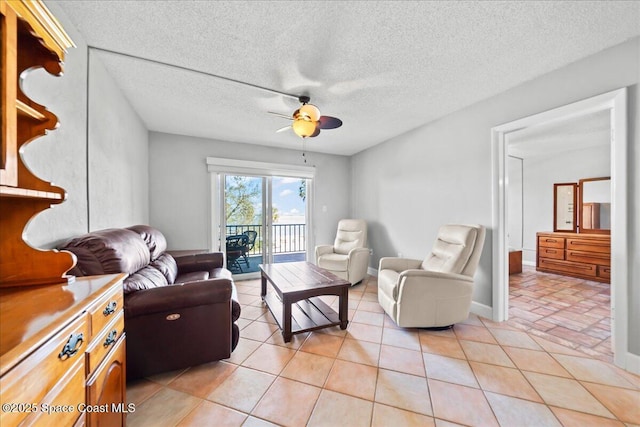 living room featuring light tile patterned floors, a textured ceiling, a ceiling fan, and baseboards