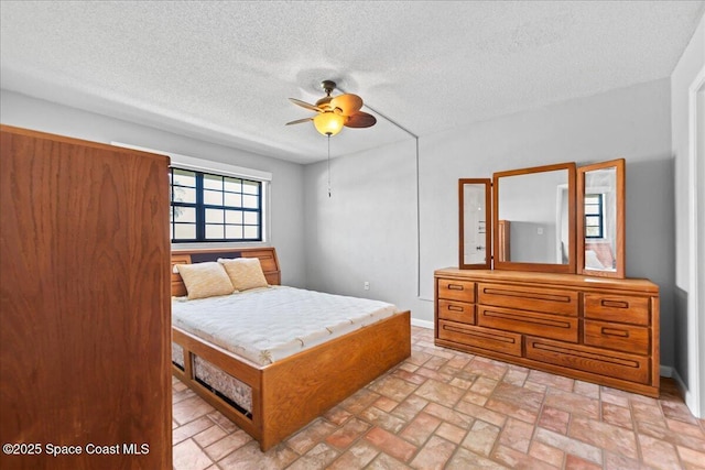 bedroom with a textured ceiling, a ceiling fan, and baseboards