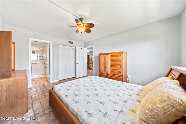 bedroom featuring stone tile floors, visible vents, baseboards, connected bathroom, and a textured ceiling