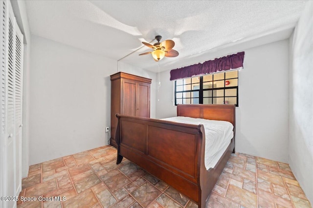 bedroom featuring a ceiling fan, stone finish floor, and a textured ceiling