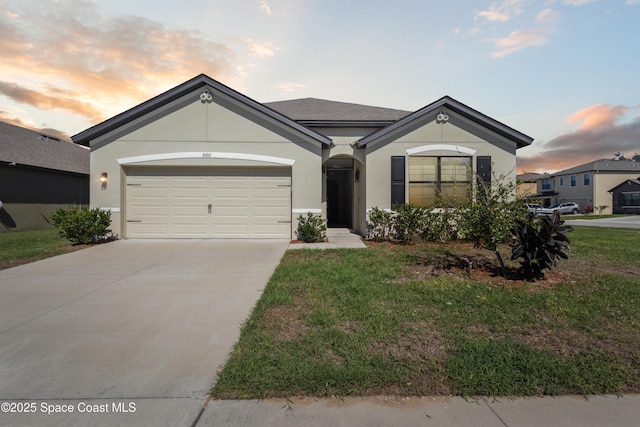 ranch-style house featuring a garage, a yard, driveway, and stucco siding