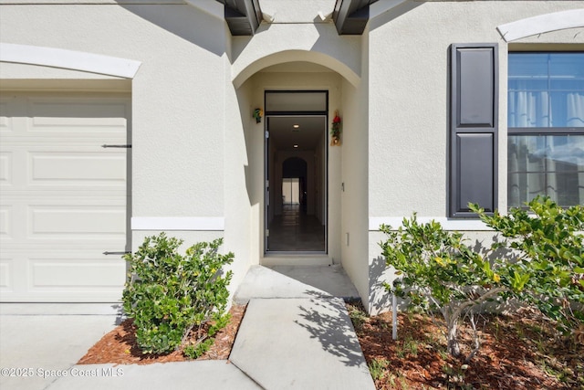 entrance to property with an attached garage and stucco siding