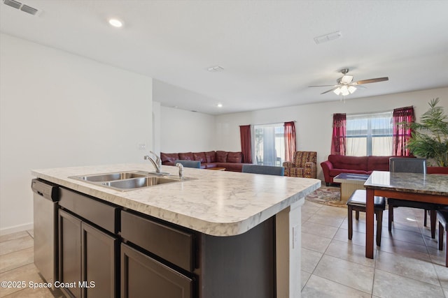 kitchen with a center island with sink, light countertops, open floor plan, a sink, and dishwasher