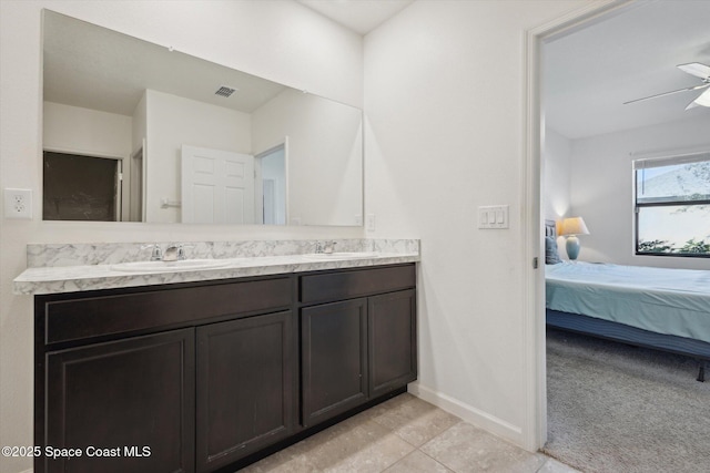 ensuite bathroom featuring visible vents, a ceiling fan, a sink, ensuite bath, and baseboards