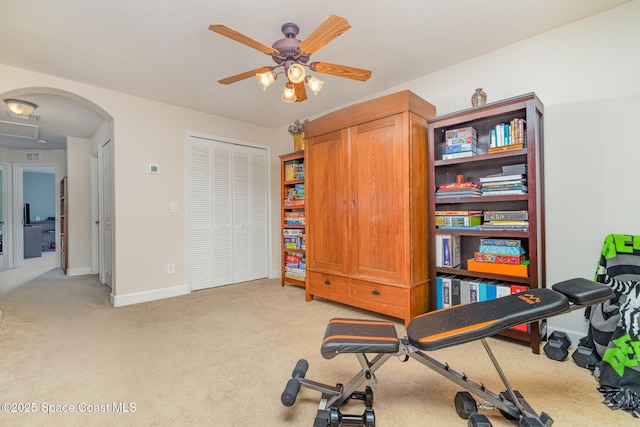 workout room with light carpet, arched walkways, baseboards, and a ceiling fan
