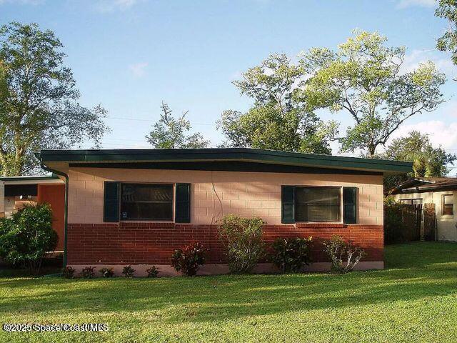 view of side of home featuring concrete block siding, brick siding, and a lawn