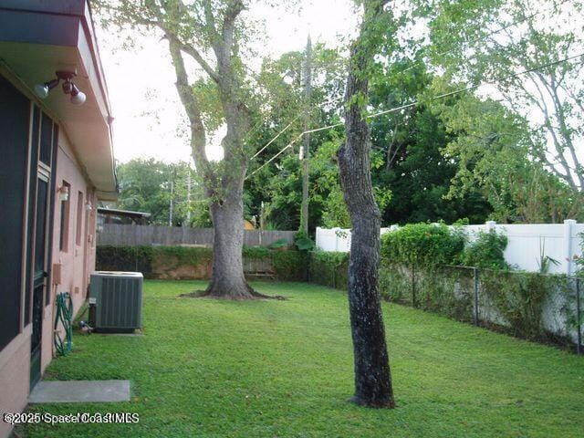 view of yard with central AC unit and a fenced backyard