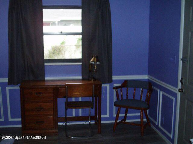 home office with wainscoting and a decorative wall