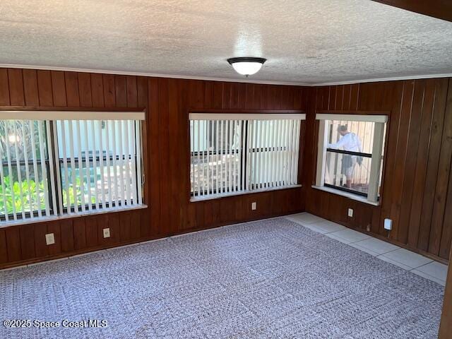 124 E Dover St E, Satellite Beach, FL 32937 - unfurnished room featuring a textured ceiling, wooden walls, healthy amount of natural light, carpet floors, and tile patterned flooring