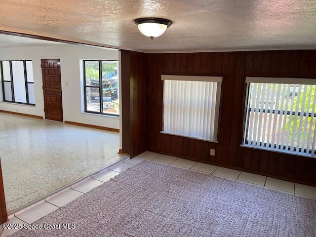 124 E Dover St E, Satellite Beach, FL 32937 - tiled empty room featuring a textured ceiling, baseboards, and wooden walls