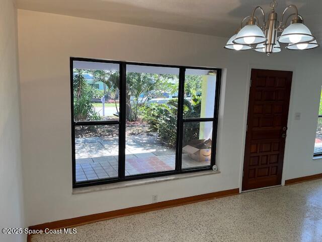124 E Dover St E, Satellite Beach, FL 32937 - spare room with baseboards, a chandelier, and speckled floor