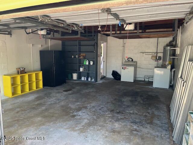 124 E Dover St E, Satellite Beach, FL 32937 - garage with freestanding refrigerator, a garage door opener, and concrete block wall