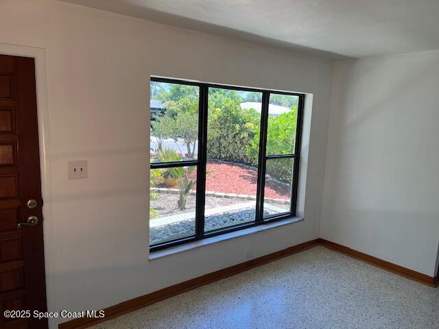 124 E Dover St E, Satellite Beach, FL 32937 - empty room featuring baseboards and dark aggregate flooring