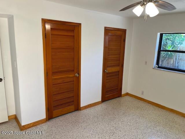 124 E Dover St E, Satellite Beach, FL 32937 - unfurnished bedroom featuring baseboards, dark aggregate flooring, and a ceiling fan
