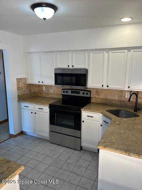 124 E Dover St E, Satellite Beach, FL 32937 - kitchen with stainless steel appliances, a sink, backsplash, white cabinetry, and light tile patterned floors