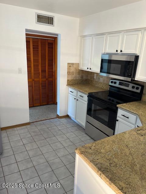 124 E Dover St E, Satellite Beach, FL 32937 - kitchen featuring stainless steel appliances, white cabinets, backsplash, and baseboards