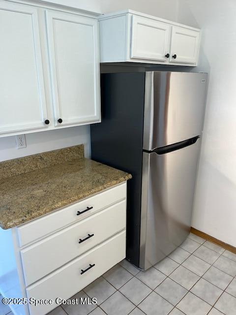 124 E Dover St E, Satellite Beach, FL 32937 - kitchen with freestanding refrigerator, white cabinetry, and light stone countertops