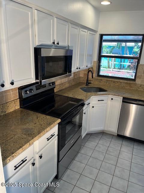 124 E Dover St E, Satellite Beach, FL 32937 - kitchen featuring stainless steel appliances, a sink, white cabinets, light tile patterned flooring, and decorative backsplash