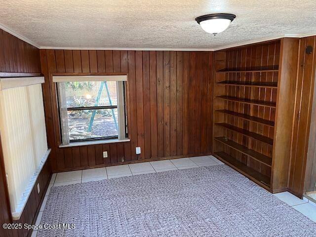 124 E Dover St E, Satellite Beach, FL 32937 - tiled empty room featuring wood walls, a textured ceiling, and carpet floors