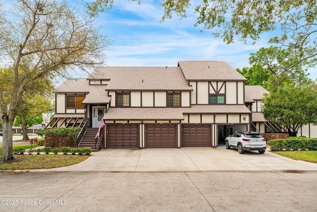 view of front of property featuring concrete driveway, roof with shingles, stairway, and stucco siding