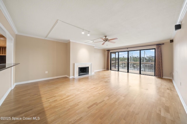 unfurnished living room featuring crown molding, a fireplace, and light wood-style flooring