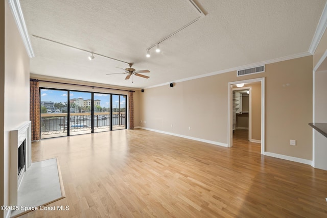 unfurnished living room with baseboards, visible vents, ornamental molding, a textured ceiling, and light wood-style floors