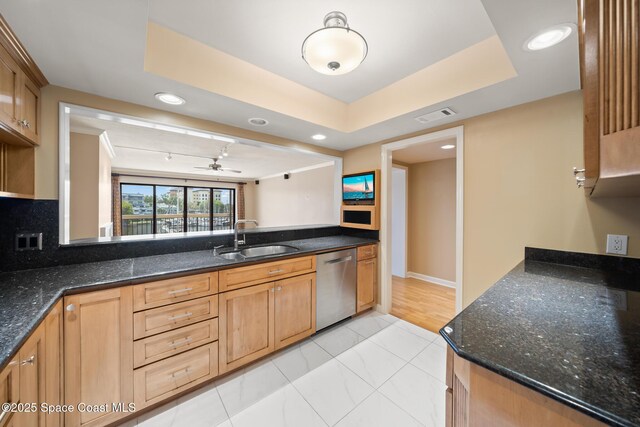 kitchen featuring dark stone counters, stainless steel dishwasher, a sink, and visible vents