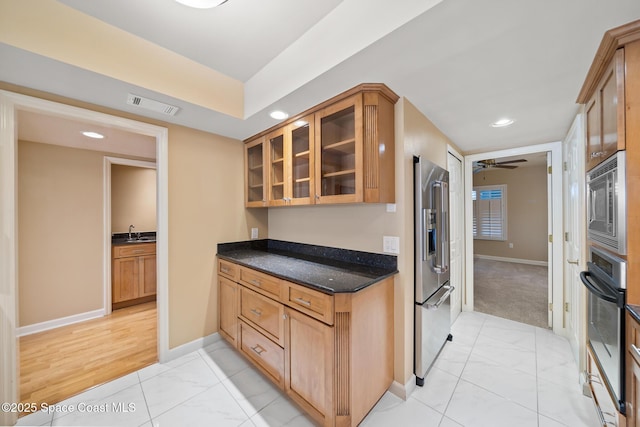 kitchen with visible vents, glass insert cabinets, appliances with stainless steel finishes, dark stone countertops, and baseboards