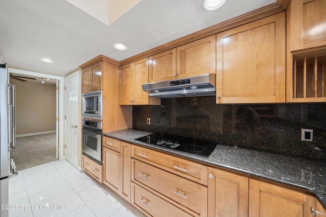 kitchen with under cabinet range hood, appliances with stainless steel finishes, backsplash, brown cabinets, and dark stone countertops