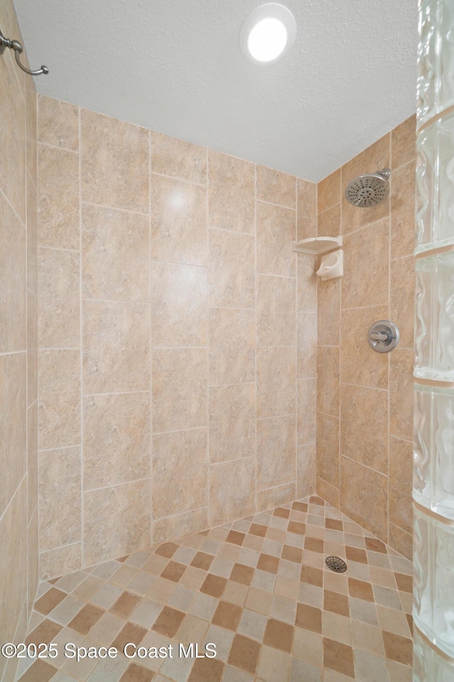 full bath with a textured ceiling and a tile shower