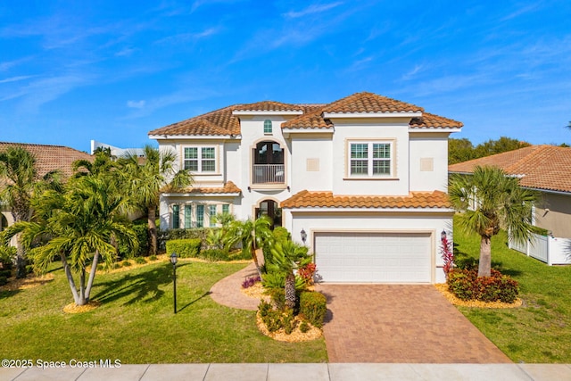 mediterranean / spanish-style home with stucco siding, an attached garage, decorative driveway, and a front lawn